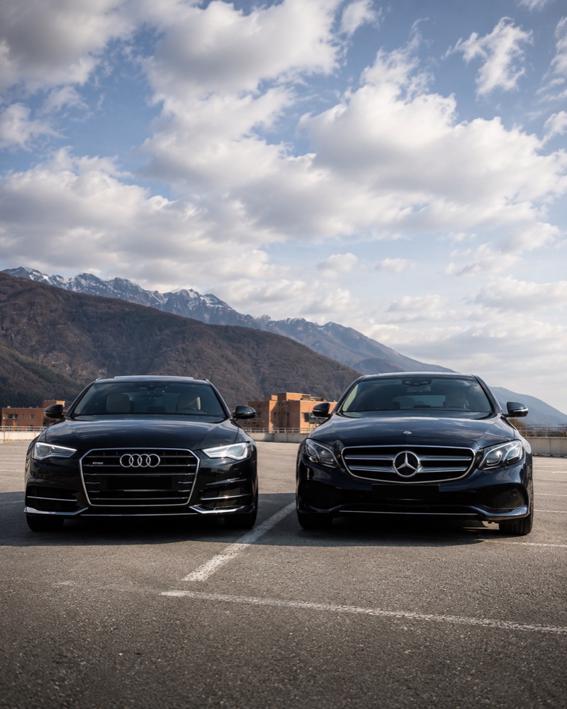 Berlina Audi e Mercedes Classe E nere con le montagne del Verbano sullo sfondo