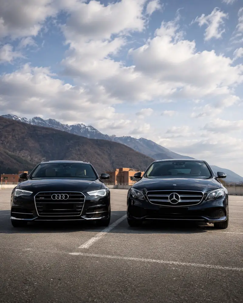 Berlina Audi e Mercedes Classe E nere con le montagne del Verbano sullo sfondo