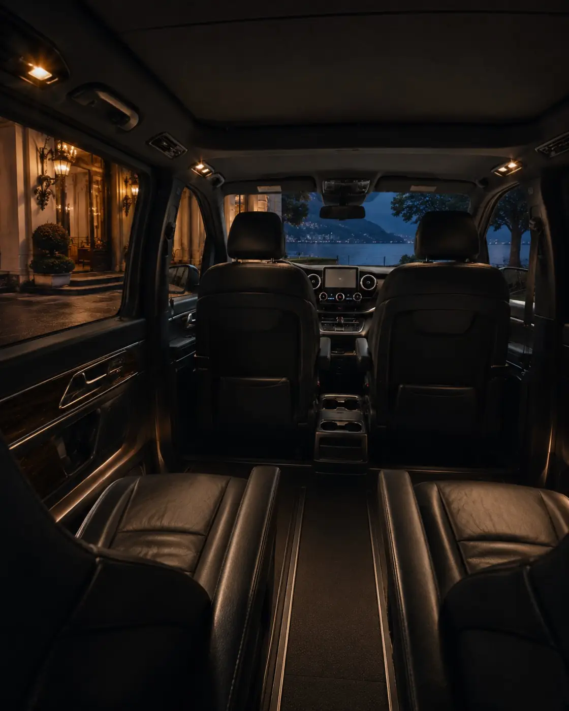 Interno del van Mercedes Classe V con sedili in pelle, la sera davanti a un hotel sul lago